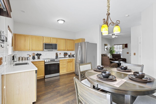 kitchen featuring light brown cabinets, sink, tasteful backsplash, decorative light fixtures, and appliances with stainless steel finishes