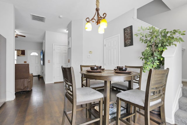 dining space with ceiling fan with notable chandelier and dark hardwood / wood-style floors