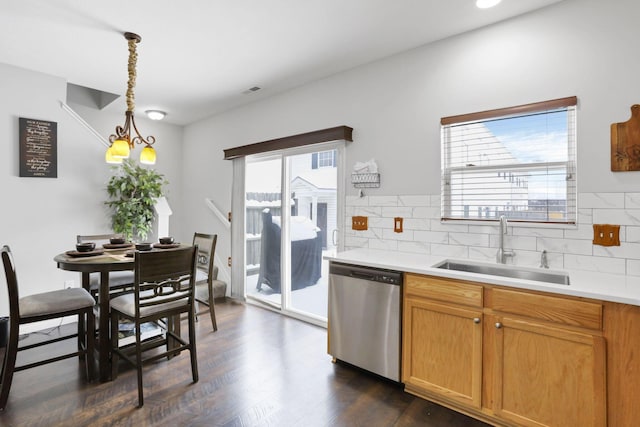 kitchen featuring decorative backsplash, stainless steel dishwasher, sink, decorative light fixtures, and dark hardwood / wood-style floors