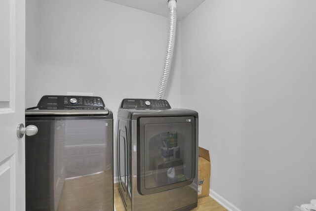 laundry room with light hardwood / wood-style floors and washer and clothes dryer