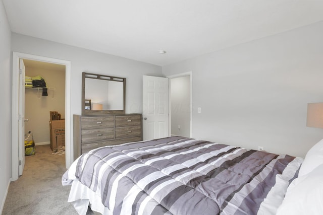 bedroom with light carpet, a walk in closet, and a closet