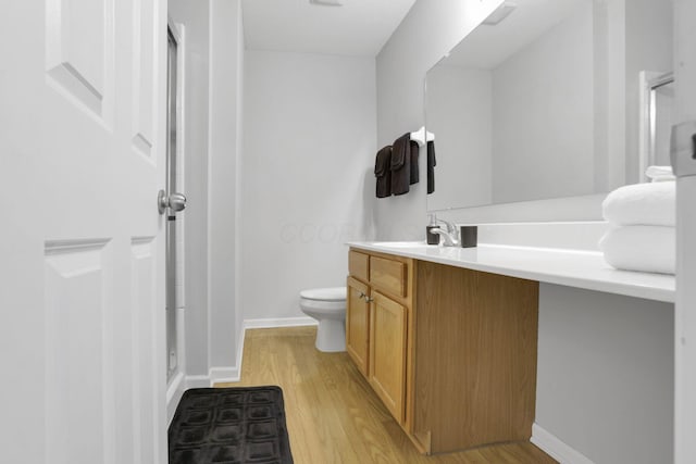 bathroom featuring toilet, vanity, a shower with door, and hardwood / wood-style flooring