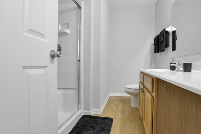 bathroom with hardwood / wood-style flooring, vanity, toilet, and a shower with door