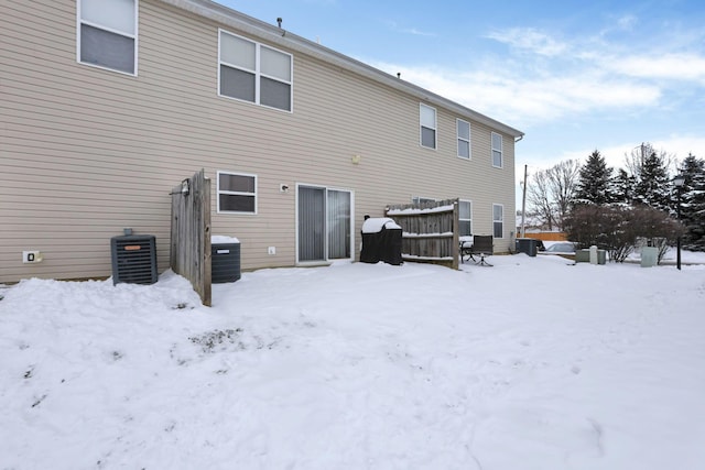 snow covered rear of property featuring central AC