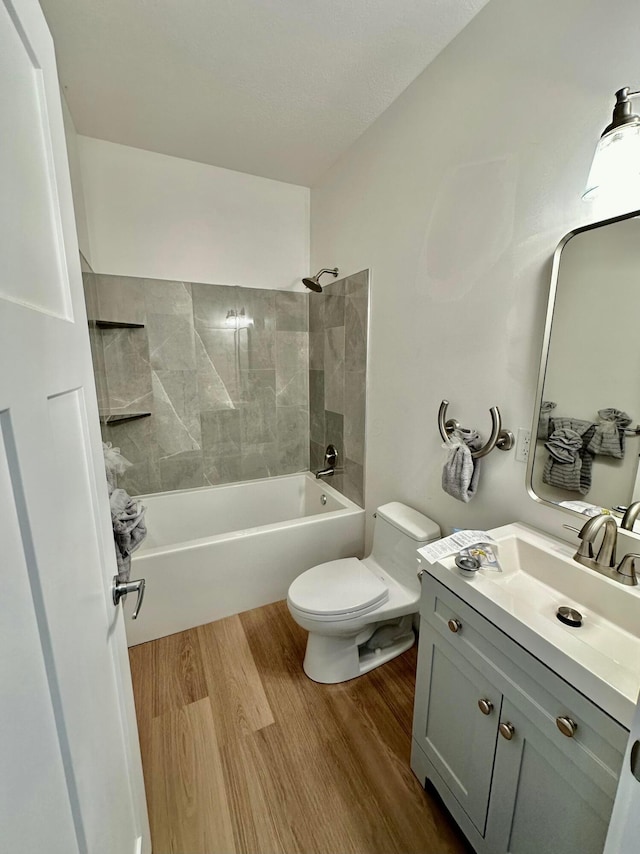 full bathroom with toilet, hardwood / wood-style floors, vanity, and tiled shower / bath