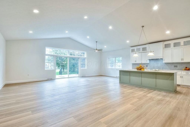 kitchen with white cabinets, tasteful backsplash, hanging light fixtures, and light hardwood / wood-style flooring