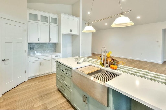 kitchen with lofted ceiling, light hardwood / wood-style flooring, decorative backsplash, decorative light fixtures, and white cabinetry