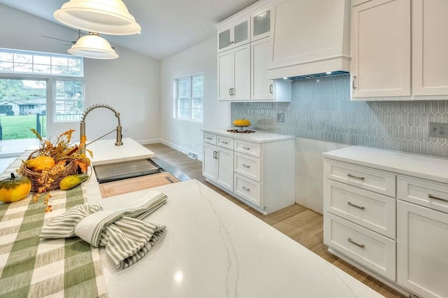 kitchen featuring white cabinets, custom range hood, decorative backsplash, and pendant lighting