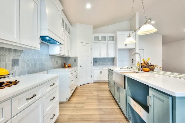 kitchen featuring hanging light fixtures, lofted ceiling, decorative backsplash, a center island with sink, and white cabinets