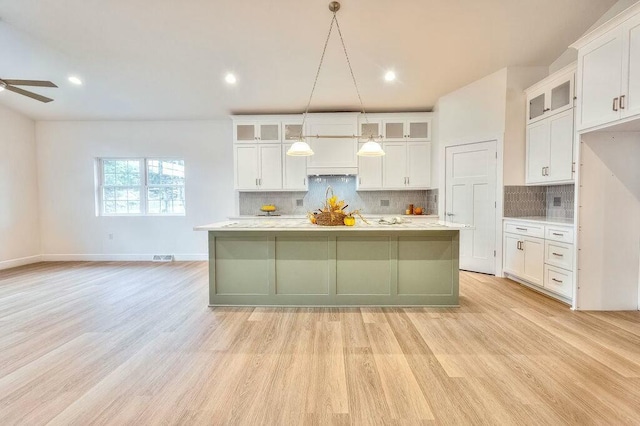 kitchen featuring white cabinetry, a kitchen island with sink, and hanging light fixtures