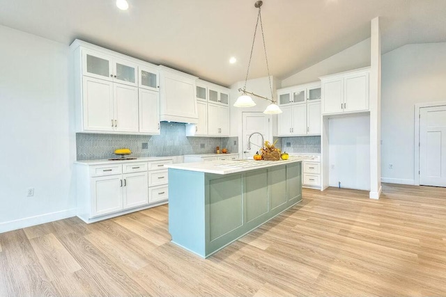 kitchen featuring a kitchen island with sink, white cabinets, hanging light fixtures, and lofted ceiling