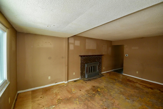 unfurnished living room featuring a textured ceiling and a brick fireplace