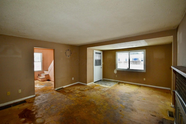 unfurnished living room with a wealth of natural light, a fireplace, and a textured ceiling