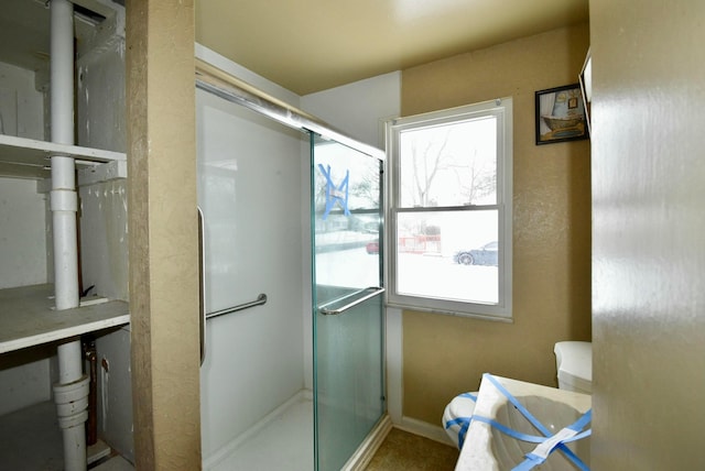 bathroom with toilet and a shower with door