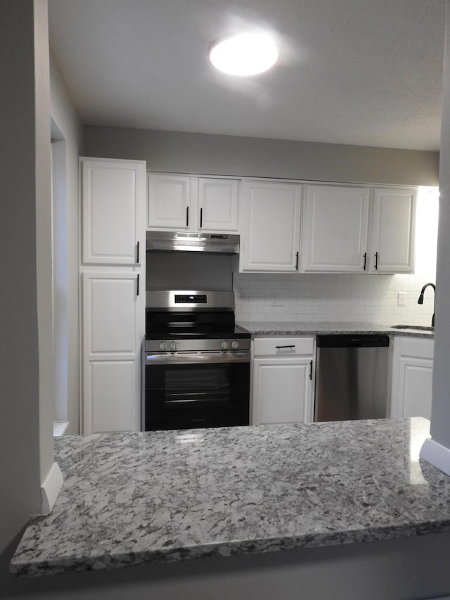 kitchen with light stone countertops, backsplash, stainless steel appliances, sink, and white cabinets