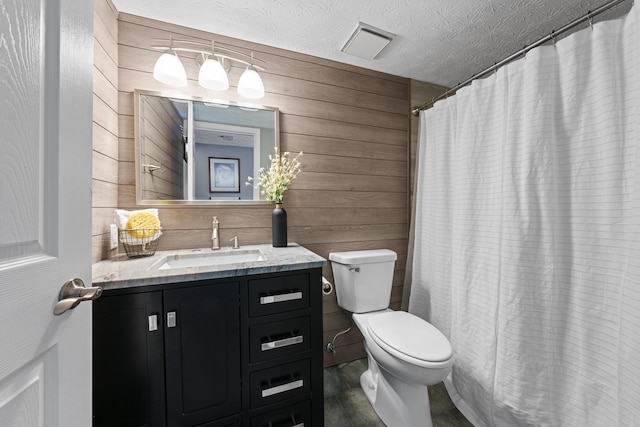 bathroom featuring toilet, a textured ceiling, wooden walls, and vanity