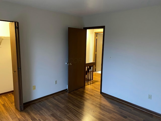 unfurnished bedroom featuring dark hardwood / wood-style flooring, a walk in closet, and a closet