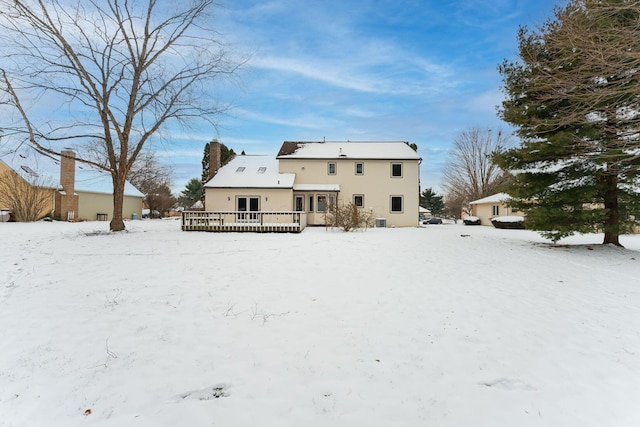 snow covered back of property with a deck