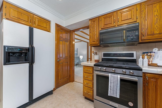 kitchen with decorative backsplash, white fridge with ice dispenser, a textured ceiling, and stainless steel range with gas stovetop