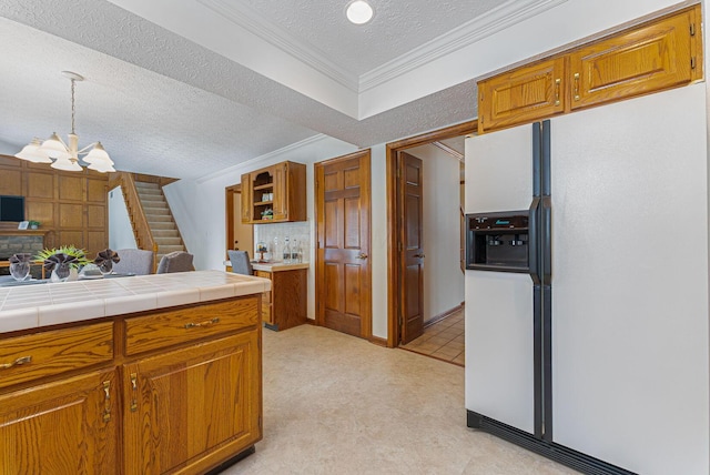 kitchen featuring an inviting chandelier, ornamental molding, white fridge with ice dispenser, a textured ceiling, and tile counters