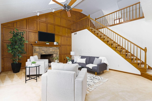 carpeted living room with ceiling fan, wood walls, a stone fireplace, and lofted ceiling