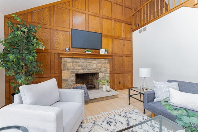 living room featuring wood walls, a stone fireplace, and light wood-type flooring