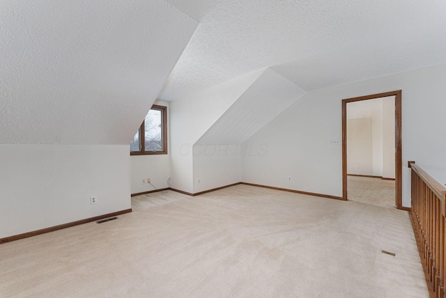 bonus room featuring a textured ceiling, light colored carpet, and lofted ceiling