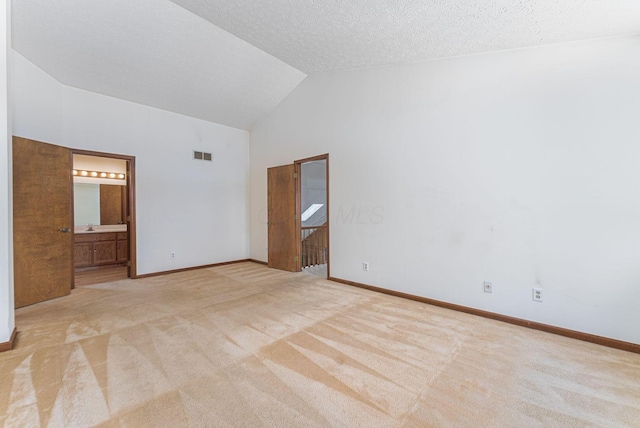 unfurnished bedroom with high vaulted ceiling, light colored carpet, a textured ceiling, and connected bathroom