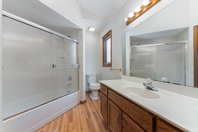 full bathroom with bath / shower combo with glass door, vanity, vaulted ceiling, hardwood / wood-style flooring, and toilet