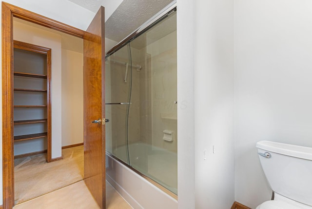 bathroom featuring toilet, a textured ceiling, and combined bath / shower with glass door