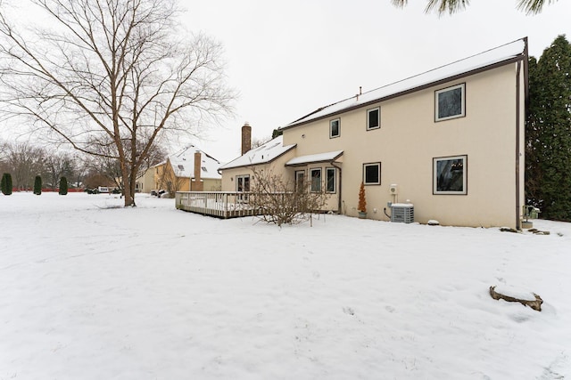 snow covered property with central AC and a wooden deck