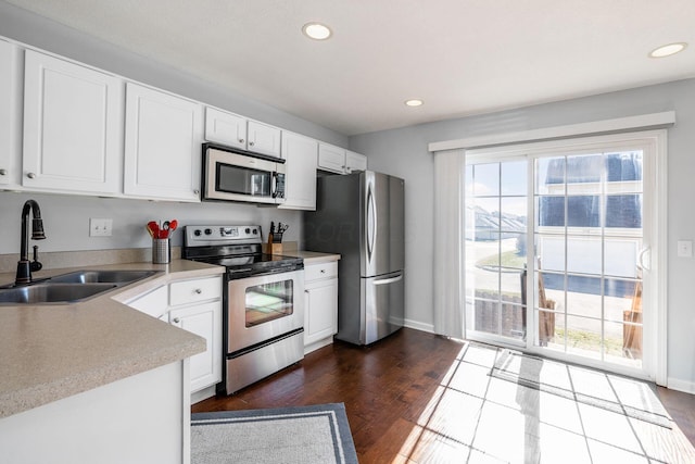 kitchen with white cabinetry, stainless steel appliances, dark hardwood / wood-style floors, and sink