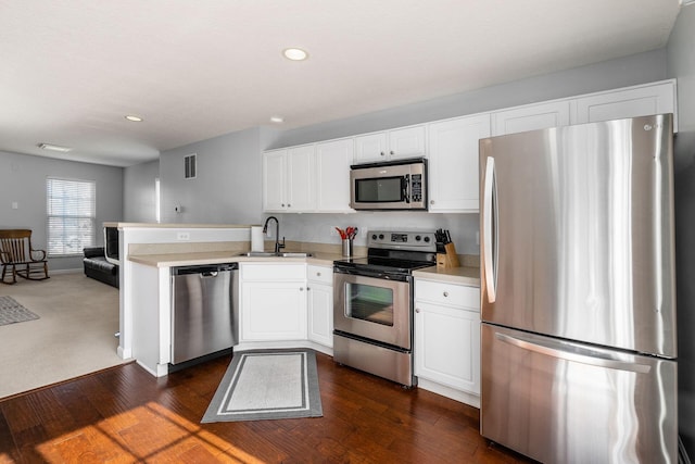 kitchen featuring sink, appliances with stainless steel finishes, dark hardwood / wood-style floors, white cabinets, and kitchen peninsula