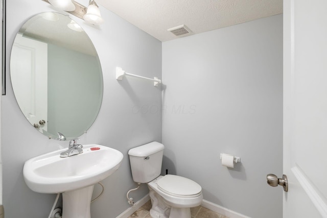 bathroom featuring tile patterned floors, a textured ceiling, and toilet