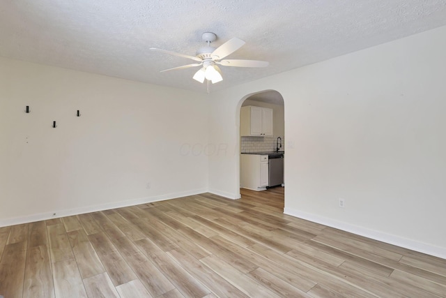 empty room featuring ceiling fan, sink, light hardwood / wood-style floors, and a textured ceiling