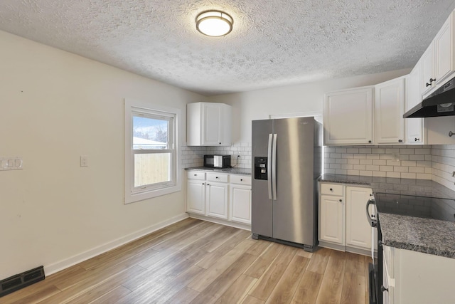 kitchen with tasteful backsplash, stainless steel fridge, white cabinets, and range with electric cooktop