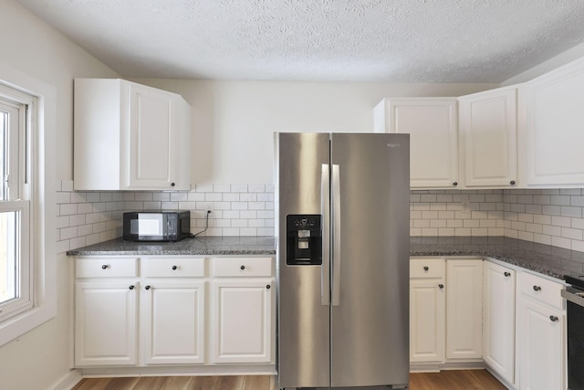 kitchen featuring decorative backsplash, white cabinetry, plenty of natural light, and stainless steel refrigerator with ice dispenser