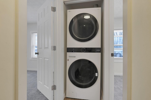 washroom with a wealth of natural light, carpet, and stacked washing maching and dryer