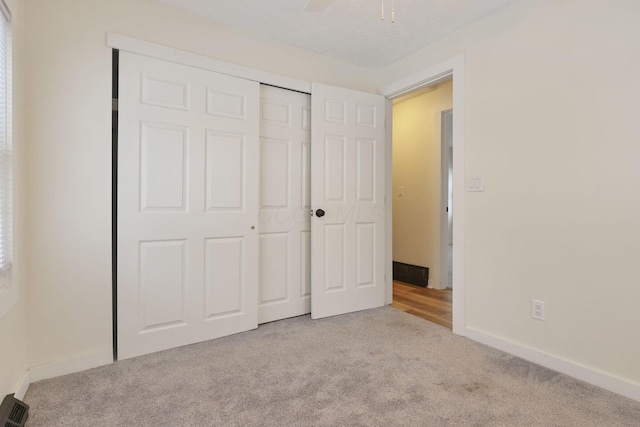 unfurnished bedroom featuring light carpet, a closet, ceiling fan, and a textured ceiling