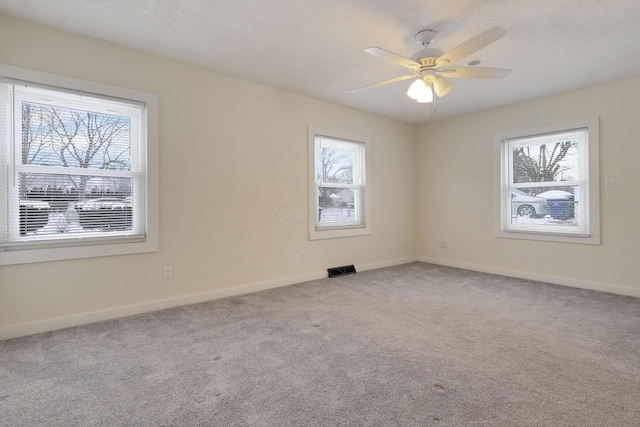 carpeted empty room featuring a wealth of natural light and ceiling fan