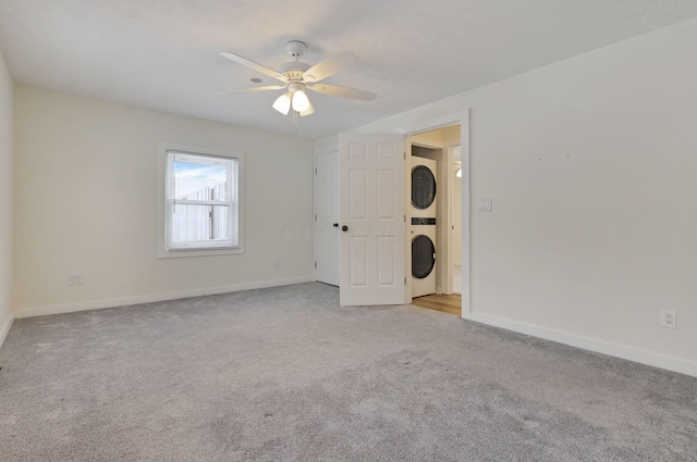 spare room with ceiling fan, light colored carpet, and stacked washer / dryer