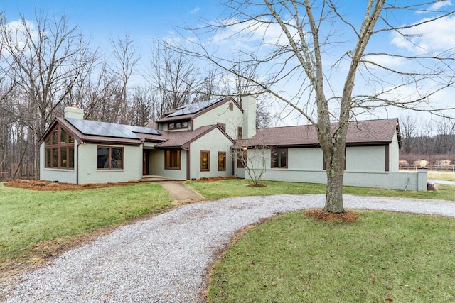 view of front of home with solar panels and a front lawn