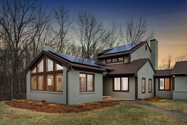 property exterior at dusk featuring solar panels and a lawn