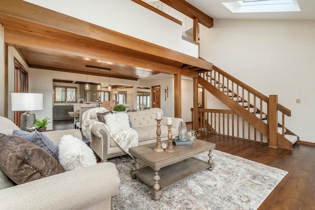 living room with beam ceiling, a skylight, and dark wood-type flooring