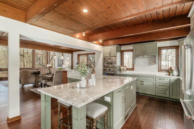 kitchen featuring tasteful backsplash, light stone counters, green cabinetry, a center island, and dark hardwood / wood-style floors