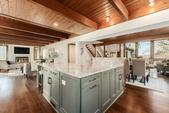 kitchen featuring light stone counters, dark wood-type flooring, beam ceiling, wooden ceiling, and a center island