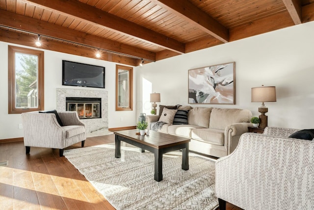 living room featuring beam ceiling, wooden ceiling, a high end fireplace, track lighting, and hardwood / wood-style flooring