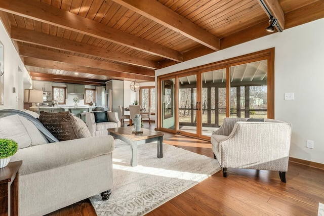 living room with track lighting, an inviting chandelier, light wood-type flooring, beam ceiling, and wood ceiling