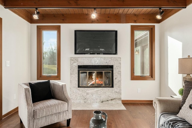 living area featuring hardwood / wood-style floors, wooden ceiling, rail lighting, a fireplace, and beamed ceiling