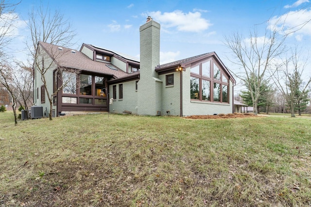 rear view of property with a lawn, a sunroom, and central AC unit